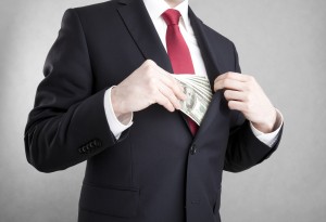 Corruption. Man putting polish money in suit jacket pocket.