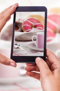 a woman using a smart phone to take a photo of some colorful donuts